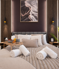 bromley-bedroom-feature-wall-hotel-style-comfort Luxury bedroom in a Bromley serviced apartment featuring a king-size bed, hotel-quality bedding and ambient feature lighting.